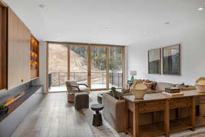 Living room featuring expansive windows, light wood finished floors, a glass covered fireplace, and recessed lighting