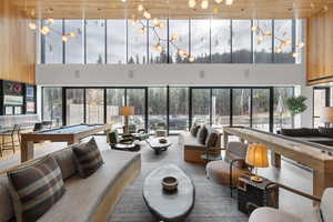 Living area with wood ceiling, pool table, a high ceiling, wood walls, and healthy amount of natural light