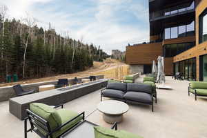 View of patio with an outdoor living space with a fire pit and a view of trees