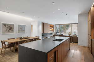 Kitchen with modern cabinets, a large island, dark stone counters, recessed lighting, and brown cabinetry
