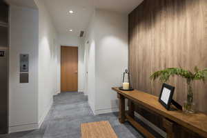 Hallway featuring recessed lighting, concrete floors, and elevator