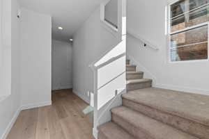 Stairway with hardwood / wood-style flooring and recessed lighting