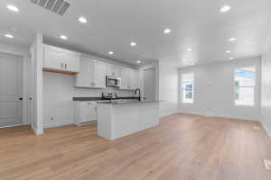 Kitchen with recessed lighting, white cabinetry, dark countertops, stainless steel appliances, and open floor plan