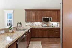 Kitchen featuring light stone counters, stainless steel appliances, dark wood-style flooring, and backsplash