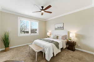 Carpeted bedroom featuring ornamental molding and ceiling fan