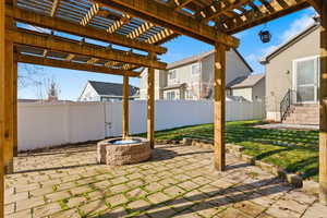 Fenced backyard with a patio area, an outdoor fire pit, and a pergola