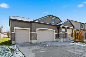 View of front of property featuring stucco siding, an attached garage, driveway, and stone siding