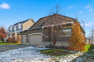 View of front of home with stucco siding, an attached garage, driveway, and covered porch