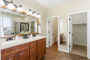 Full bath featuring double vanity, a spacious closet, a shower stall, and dark wood finished floors