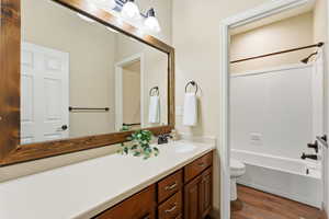 Full bath featuring vanity, washtub / shower combination, and dark wood finished floors