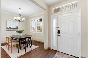 Foyer entrance featuring ornamental molding, dark wood finished floors, and a chandelier
