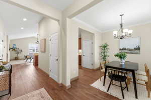 Dining area featuring wood finished floors, vaulted ceiling, a chandelier, recessed lighting, and crown molding