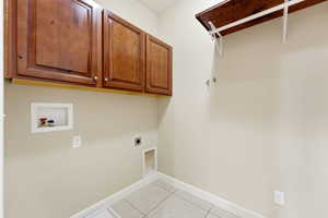 Laundry room with washer hookup, hookup for an electric dryer, light tile patterned floors, and cabinet space