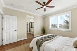Bedroom with ensuite bath, crown molding, wood finished floors, and a ceiling fan
