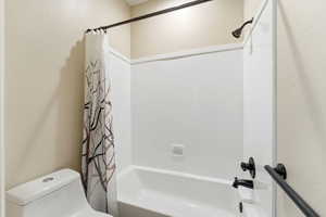 Bathroom with shower / tub combo with curtain and toilet