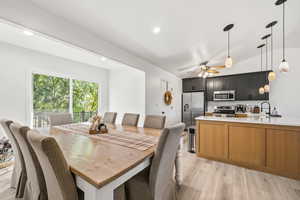 Dining room with light wood finished floors, lofted ceiling, recessed lighting, and a ceiling fan