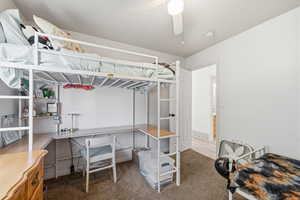 Bedroom with dark colored carpet and a ceiling fan