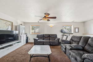 Carpeted living area featuring a textured ceiling and ceiling fan