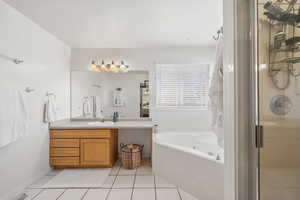 Bathroom with vanity, a whirlpool tub, light tile patterned floors, and a shower stall