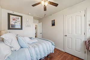 Bedroom with wood finished floors, attic access, ceiling fan, and a textured ceiling