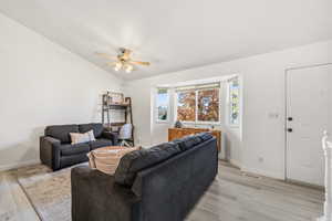 Living room with light wood-type flooring, vaulted ceiling, and ceiling fan