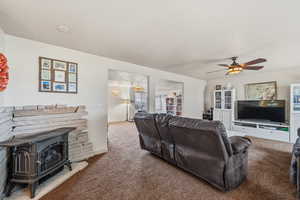 Carpeted living room featuring a wood stove and ceiling fan