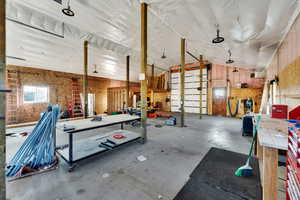 Misc room with vaulted ceiling, concrete flooring, a workshop area, and a heating unit