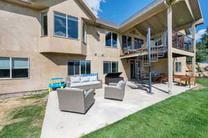 Rear view of house featuring outdoor lounge area, a patio, stucco siding, and a balcony
