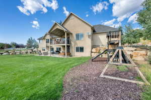 Rear view of property featuring a patio area, a playground, stucco siding, a yard, and a balcony