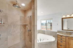 Full bath featuring a tub with jets, a shower stall, vanity, and recessed lighting