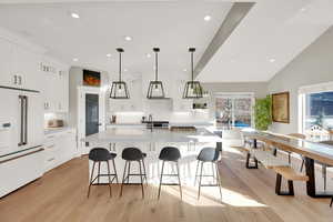 Kitchen featuring high end fridge, a large island, a kitchen breakfast bar, pendant lighting, and light wood-style flooring