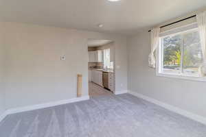 Empty room with light colored carpet and a textured ceiling