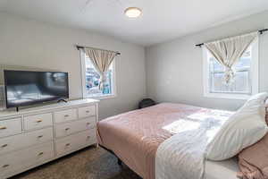 Bedroom with dark colored carpet and a textured ceiling