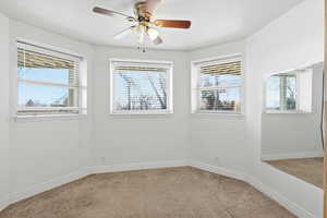 Spare room with healthy amount of natural light, ceiling fan, and light carpet