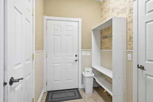 Mudroom featuring wainscoting, wallpapered walls, and light tile patterned flooring