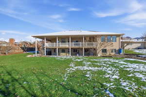 Rear view of property featuring a yard, a patio area, and a balcony