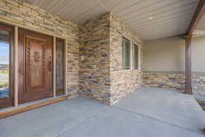 Doorway to property with stone siding and a patio
