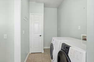 Laundry area featuring light tile patterned flooring and independent washer and dryer