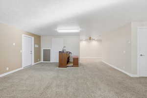 Empty room with light colored carpet, a textured ceiling, and a ceiling fan