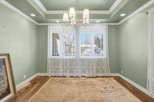 Unfurnished dining area with recessed lighting, wood finished floors, a raised ceiling, ornamental molding, and a chandelier