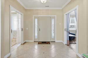 Entrance foyer featuring crown molding and baseboards