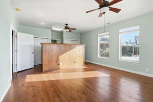 Unfurnished living room featuring wood finished floors and a ceiling fan