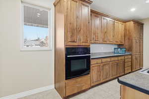 Kitchen featuring brown cabinetry, oven, recessed lighting, and light tile patterned flooring
