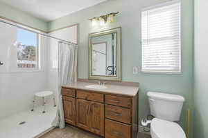 Full bath with a shower stall, vanity, and light tile patterned flooring