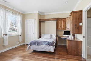 Bedroom featuring ornamental molding, dark wood-type flooring, and built in desk