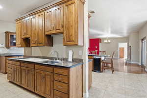 Kitchen with dark countertops, brown cabinets, a chandelier, and light tile patterned floors