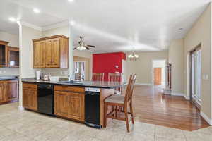 Kitchen with a kitchen breakfast bar, dark countertops, brown cabinetry, dishwasher, and a peninsula