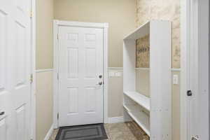 Mudroom with wainscoting, wallpapered walls, and tile patterned flooring
