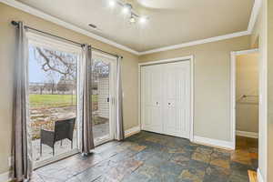Entryway featuring stone tile flooring and ornamental molding