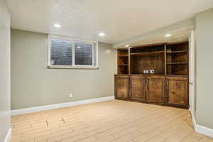 Bar featuring dark brown cabinetry, wood finish floors, recessed lighting, a textured ceiling, and open shelves